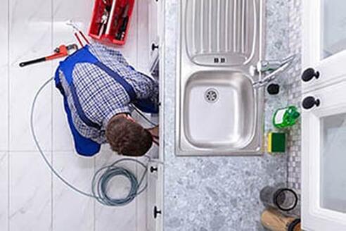 Geelong plumber performing home plumbing installation under kitchen sink