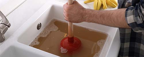 Geelong plumber using a plunger to unblock a blocked drain